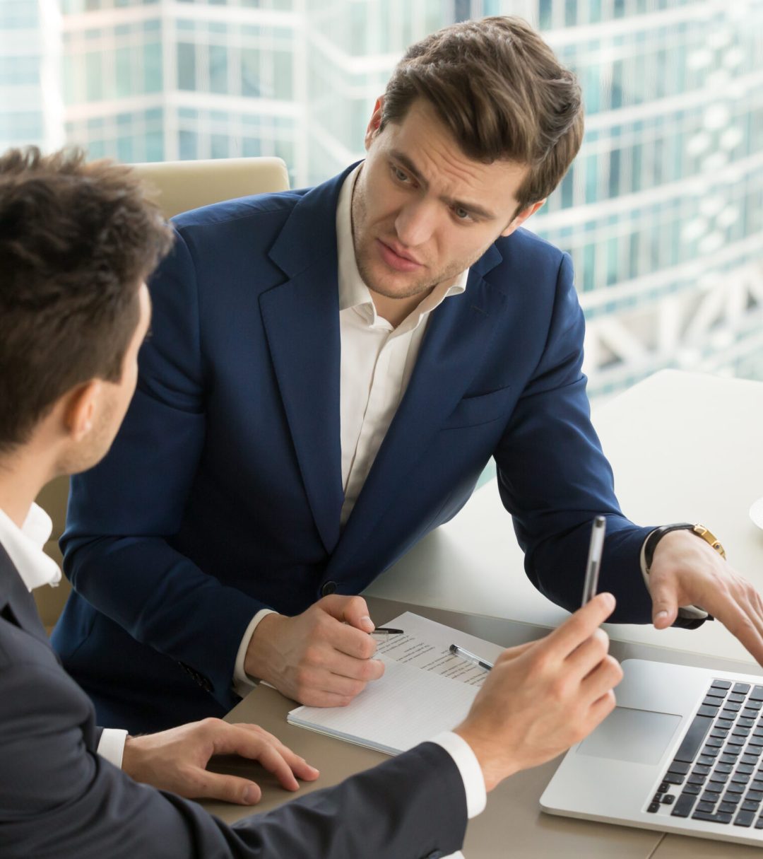 Two,Serious,Businessmen,Using,Laptop,And,Discussing,New,Project,At